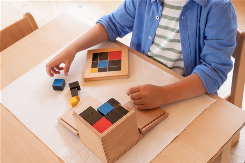 Niño usando el material Montessori del Binomio de madera